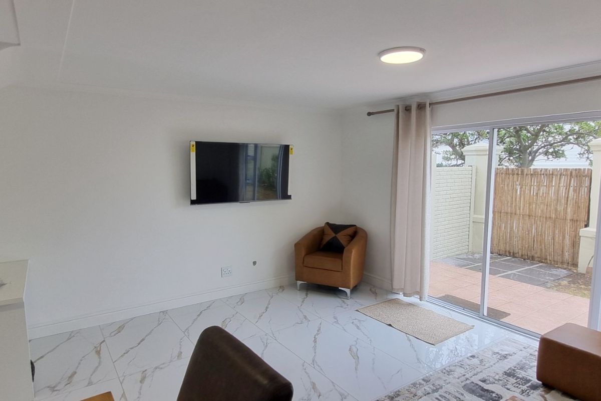 Bright living area featuring modern marble-look floor tiles, built-in shelving, and large sliding glass doors providing direct access to the outdoor patio.