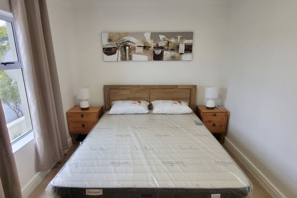 A well-maintained bedroom featuring neutral walls, a window with curtains, and clean flooring.