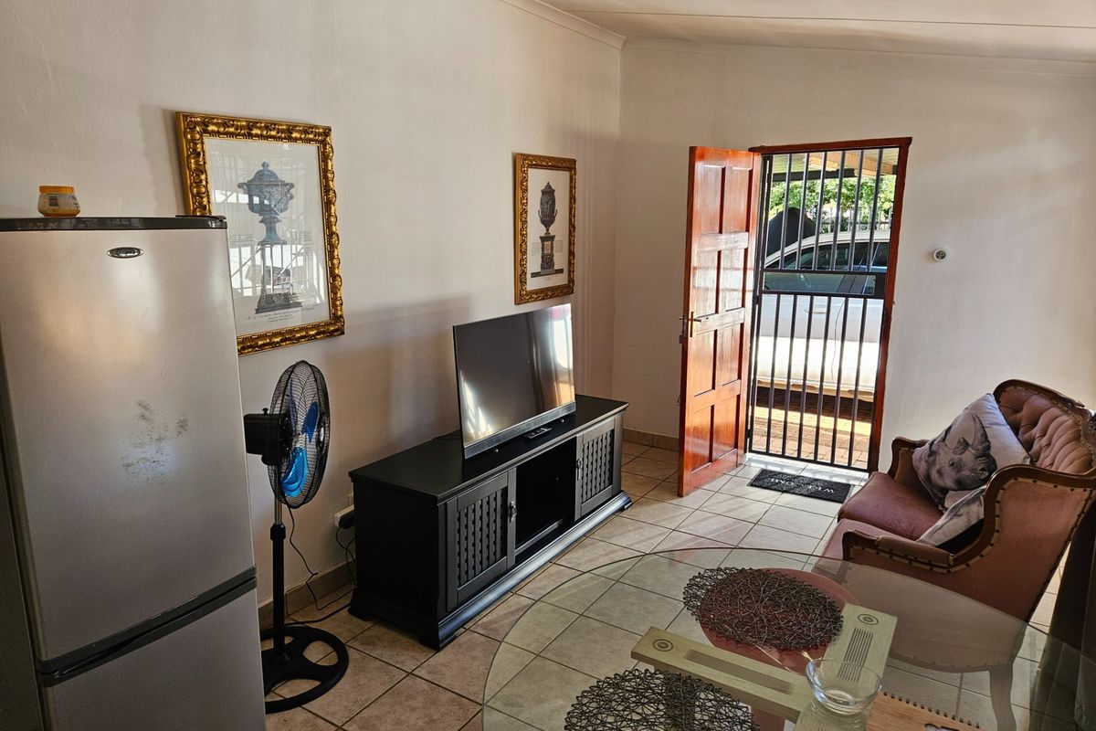 A living area featuring tiled flooring and direct access to the exterior through a timber door with an integrated security gate.