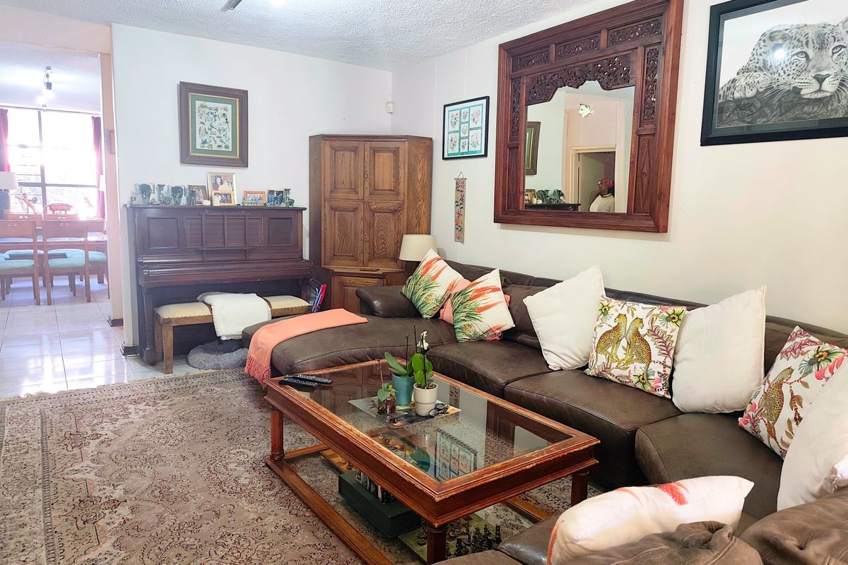 A spacious living room featuring tiled flooring and an open-plan layout that flows into the adjacent dining area.