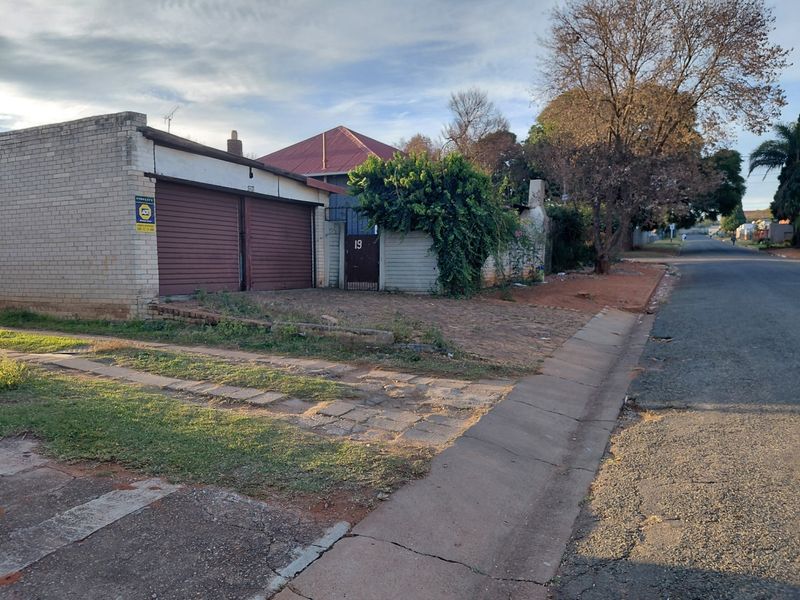 Street-facing view of the property featuring a double garage, paved driveway, and perimeter wall with gated entrance.