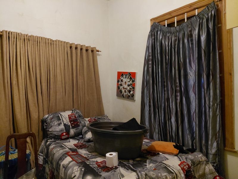 A bedroom featuring two windows with heavy curtains and plain wall finishes.