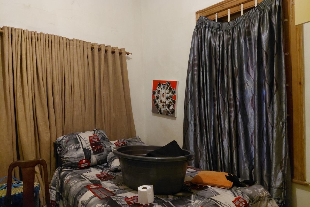 A bedroom featuring two windows with heavy curtains and plain wall finishes.