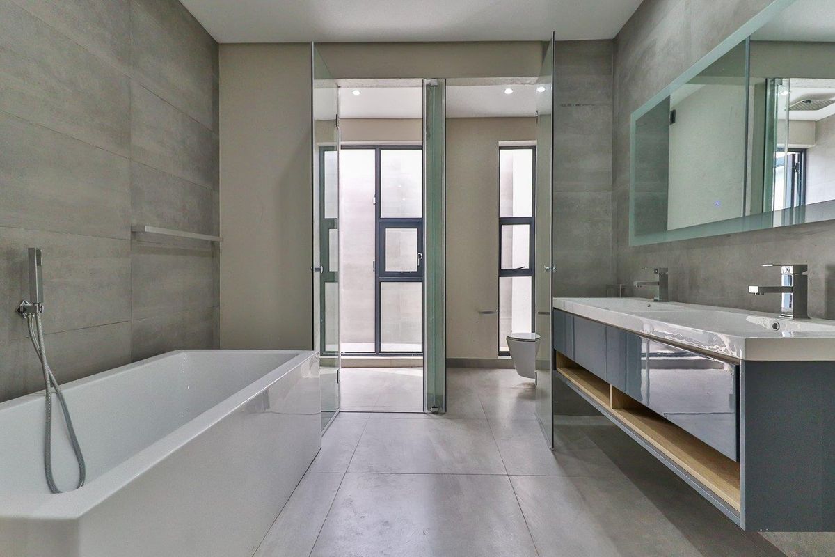 Modern, spacious bathroom featuring a freestanding bathtub, double vanity with contemporary cabinetry, and large format tiling throughout for a clean, minimalist aesthetic.