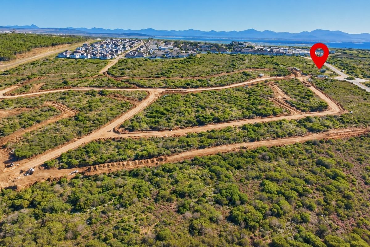 Aerial view of a residential development site featuring cleared plots, unpaved access roads, and surrounding coastal landscape.