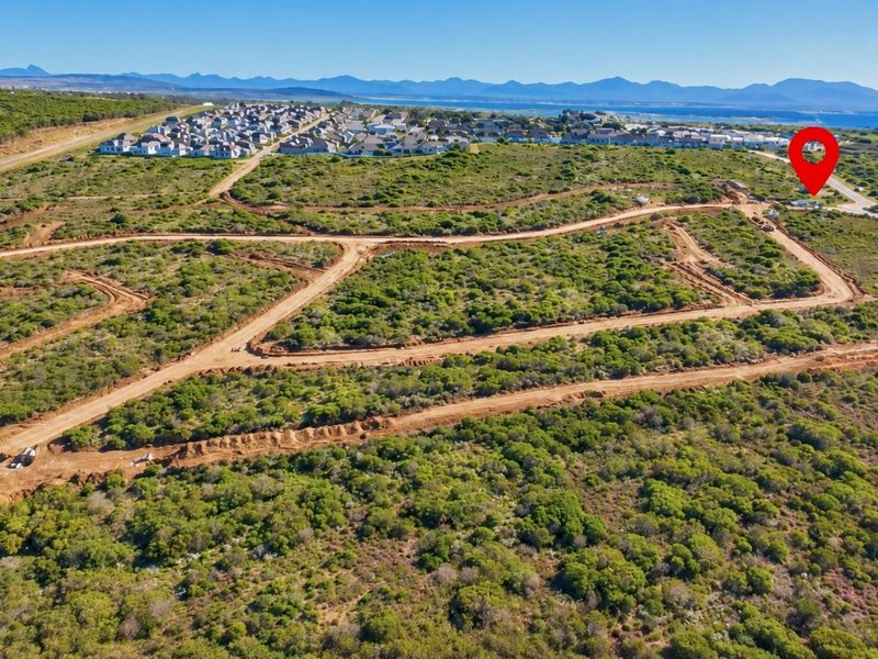 Aerial view of a residential development site featuring cleared land plots and unpaved access roads in a coastal setting.