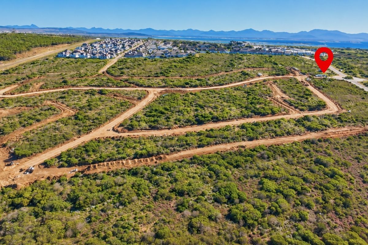 Aerial view of a residential development site featuring cleared land plots and unpaved access roads in a coastal setting.