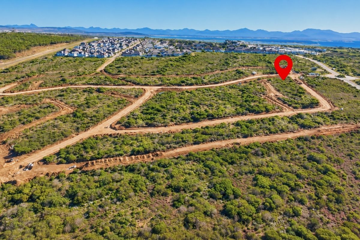 Aerial view of a vacant residential land plot within a developing estate, featuring natural coastal vegetation and established dirt access roads.