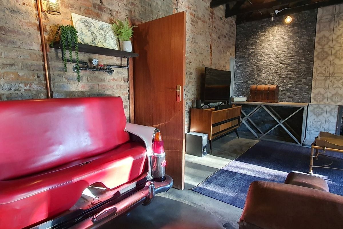 A rustic living room featuring exposed brick walls, a stone-clad fireplace surround, and decorative patterned wall tiles.