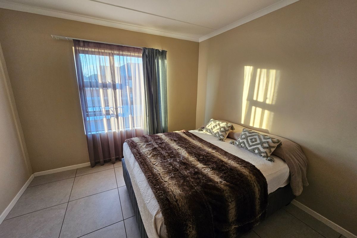A bedroom featuring tiled flooring and a window with curtain tracks, providing natural light and a neutral wall finish.