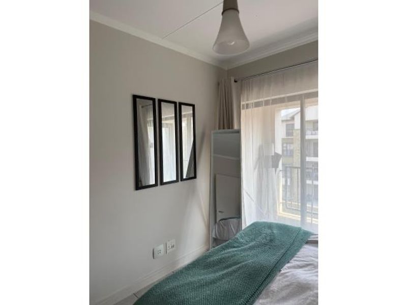 A bright bedroom featuring a sliding glass door that opens to a balcony, providing natural light and access to outdoor space.