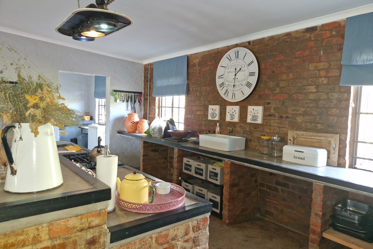 Rustic farmhouse kitchen featuring exposed brick walls, concrete countertops, and a farmhouse-style sink, offering a charming and character-filled culinary space.