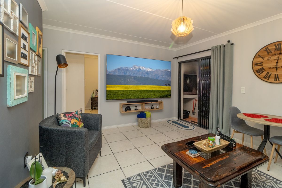 A living room featuring tiled flooring, a wall-mounted television, and sliding glass doors leading to an outdoor area.