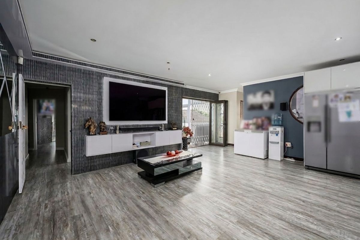 Spacious living room featuring modern laminate flooring, recessed downlighting, and a custom built-in media console with integrated storage.