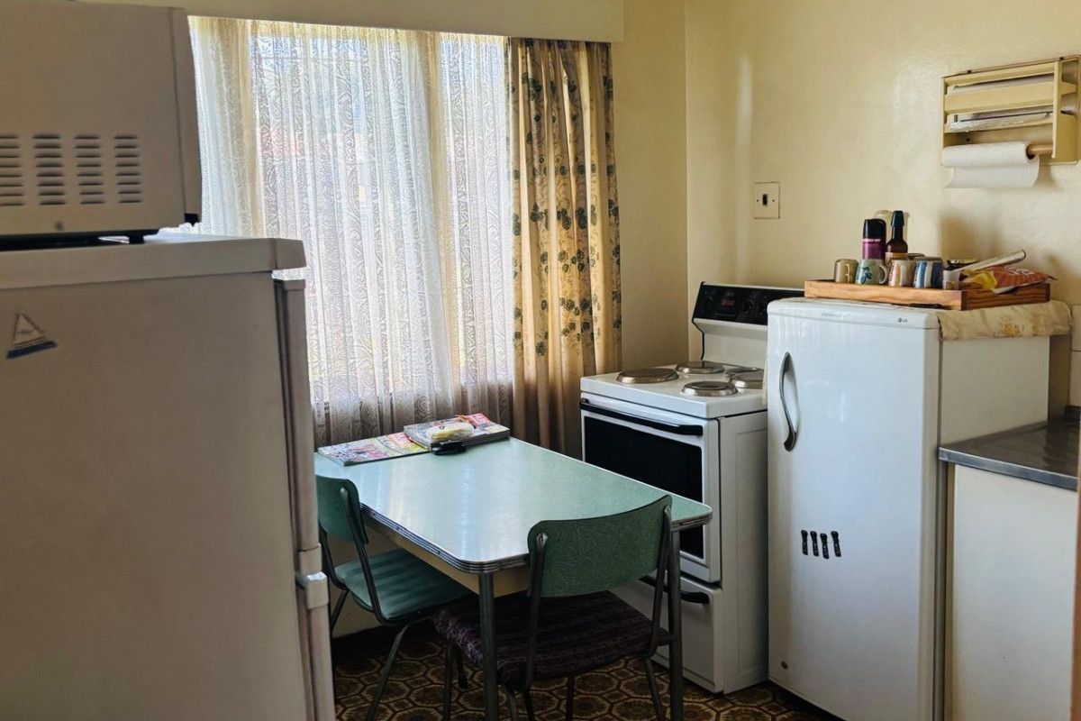 A dated kitchen featuring original cabinetry, a freestanding stove, and vintage patterned flooring, offering significant potential for a modern renovation.