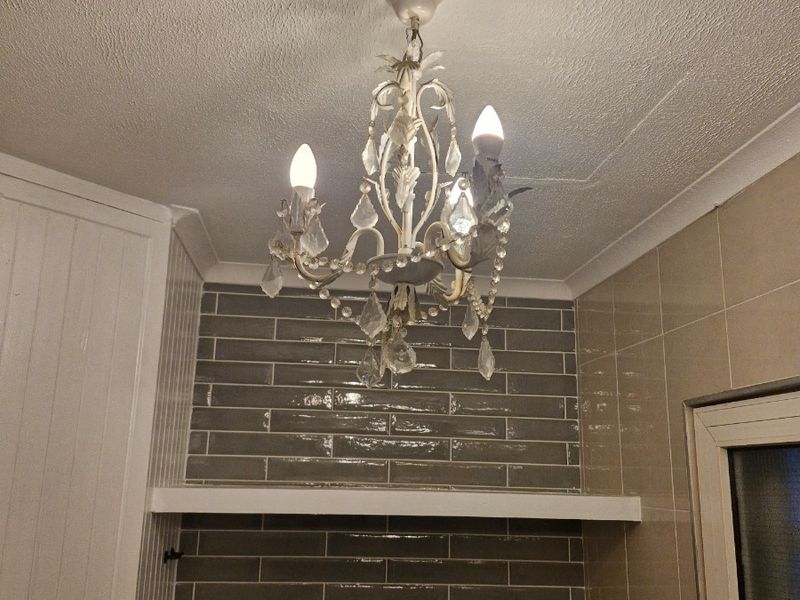 A kitchen area featuring a grey subway tile backsplash, granite countertop, and a decorative chandelier light fixture.