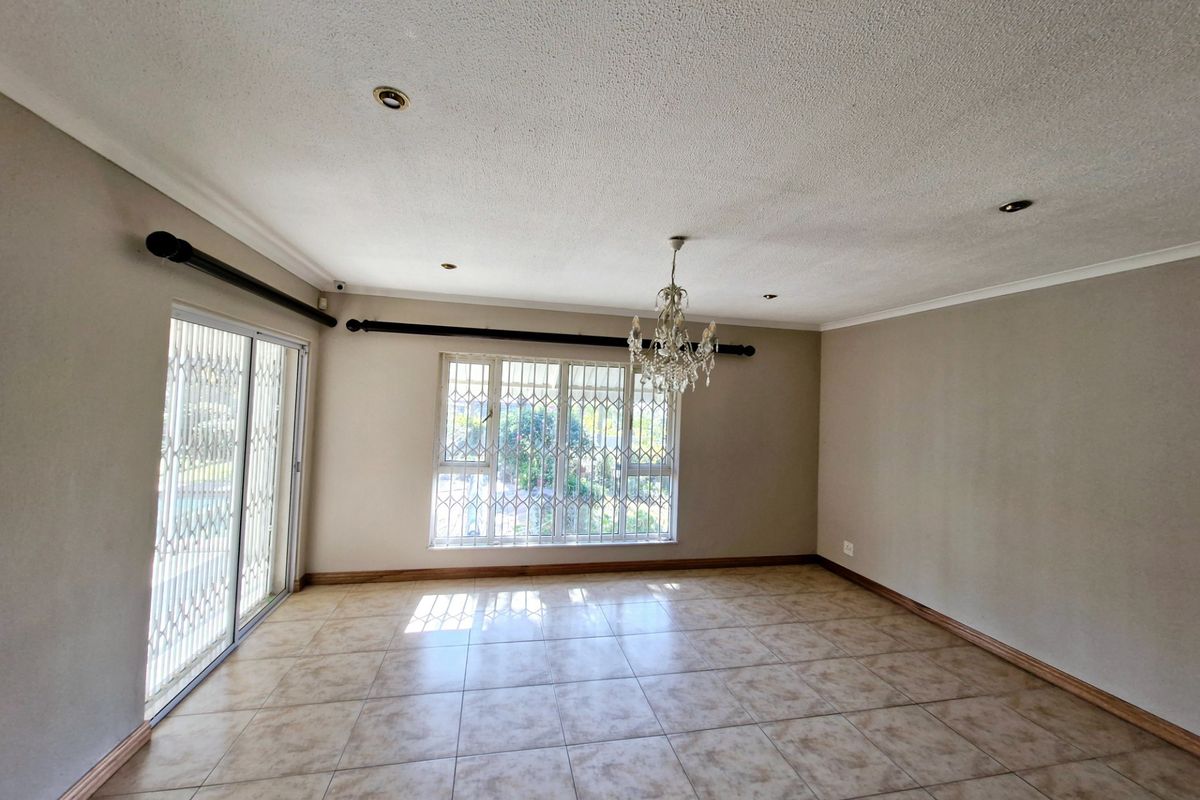 Spacious living area featuring tiled flooring, recessed lighting, and sliding glass doors with security gates, offering natural light and access to the exterior.