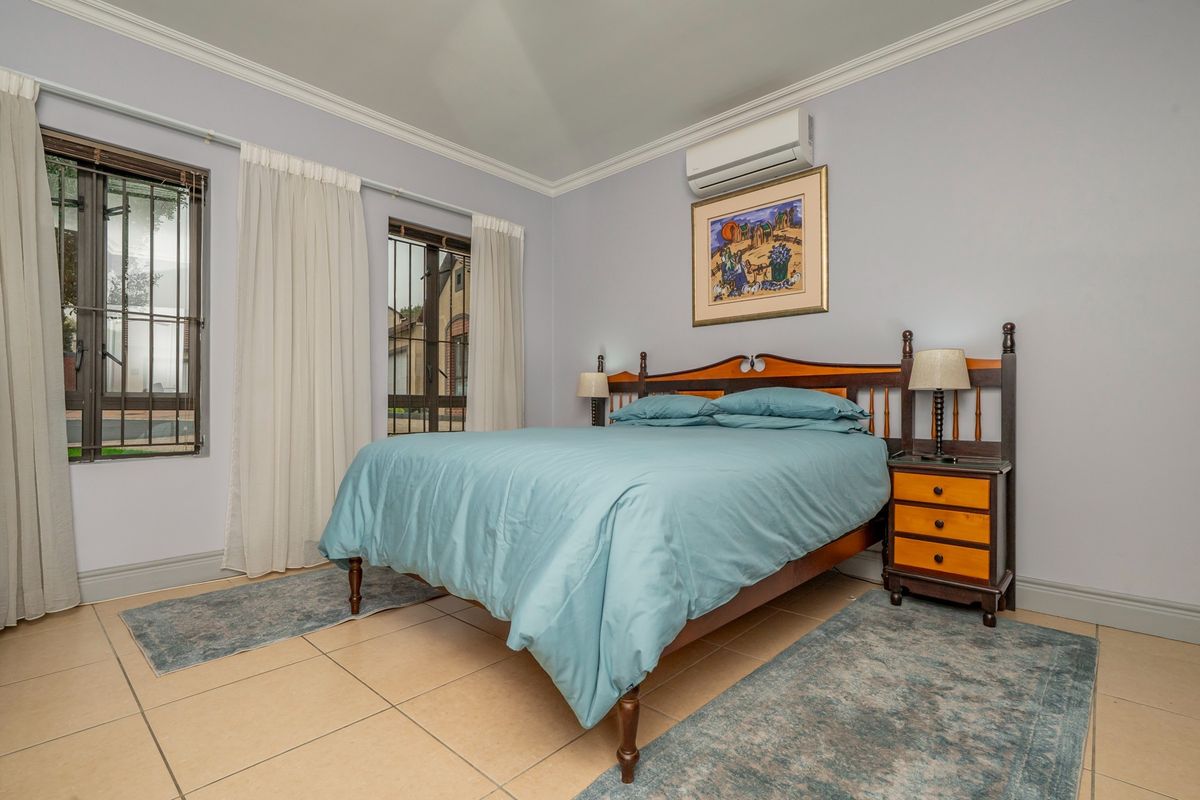 A well-maintained bedroom featuring tiled flooring, crown molding, and a wall-mounted air conditioning unit.