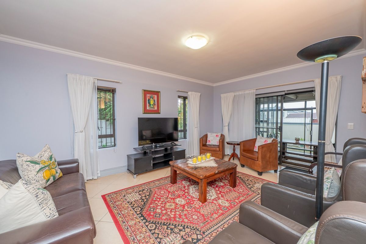 A spacious living room featuring tiled flooring, crown molding, and large sliding glass doors that provide access to the outdoor patio area.