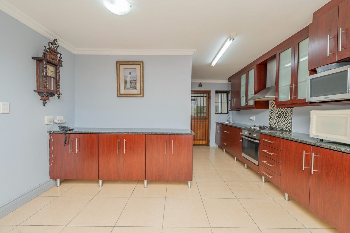 A functional kitchen featuring dark wood cabinetry, granite countertops, a built-in oven, gas hob, and tiled flooring.