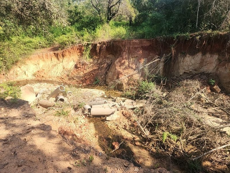 A view of a natural watercourse on the property showing significant soil erosion and exposed earth banks with scattered debris.