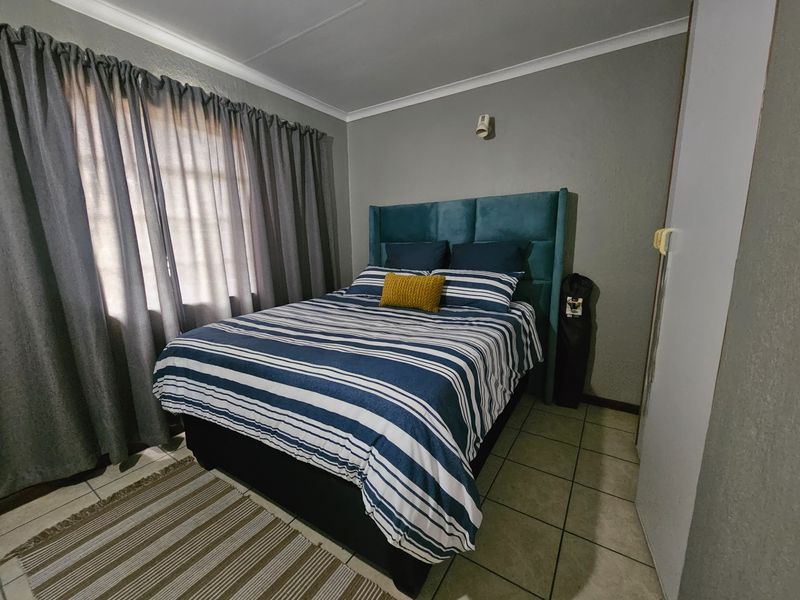 A functional bedroom featuring tiled flooring, neutral wall finishes, and a built-in cupboard, providing a comfortable and practical living space.