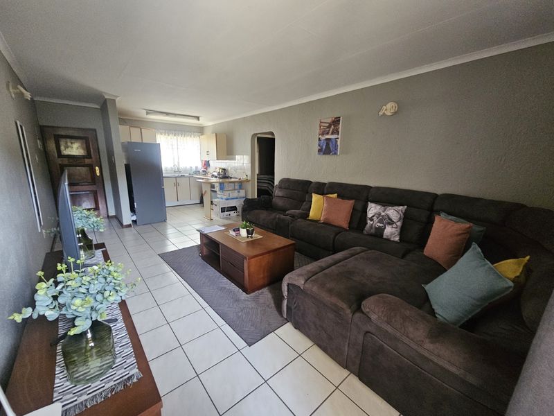 Open-plan living area featuring tiled flooring, a connected kitchen space, and direct access to the entrance.