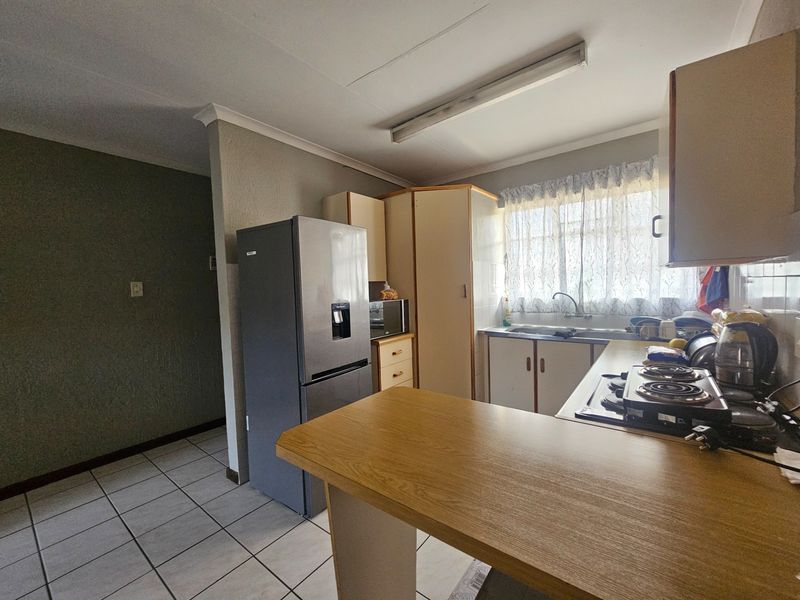 Functional kitchen featuring built-in cabinetry, a breakfast bar, integrated hob, and a stainless steel sink with window view.