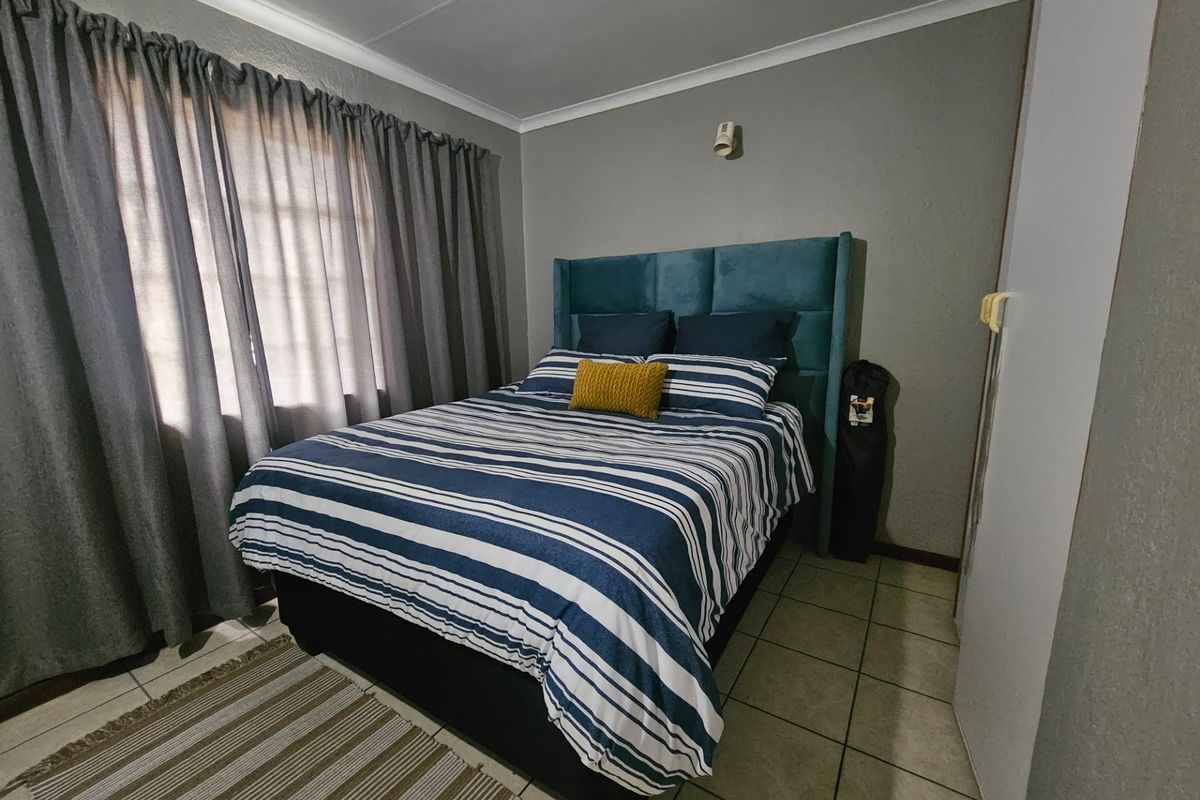 A functional bedroom featuring tiled flooring, neutral wall finishes, and a built-in cupboard, providing a comfortable and practical living space.