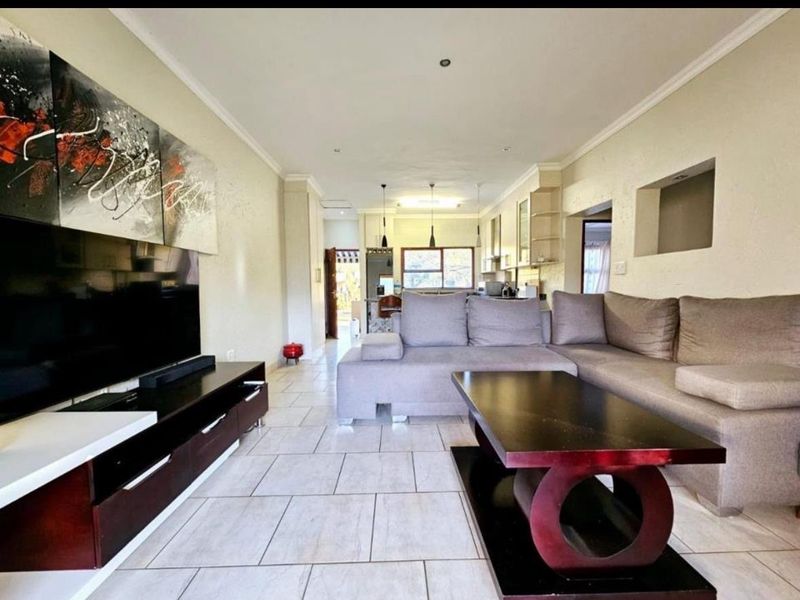 Spacious open-plan living area featuring tiled flooring, recessed lighting, and a seamless flow into the kitchen space.