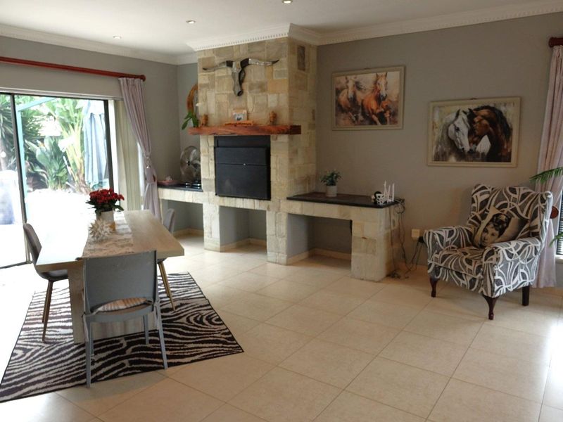 Spacious living area featuring a prominent stone fireplace with timber mantelpiece, ceramic tiled flooring, and large sliding doors providing access to the outdoor patio.