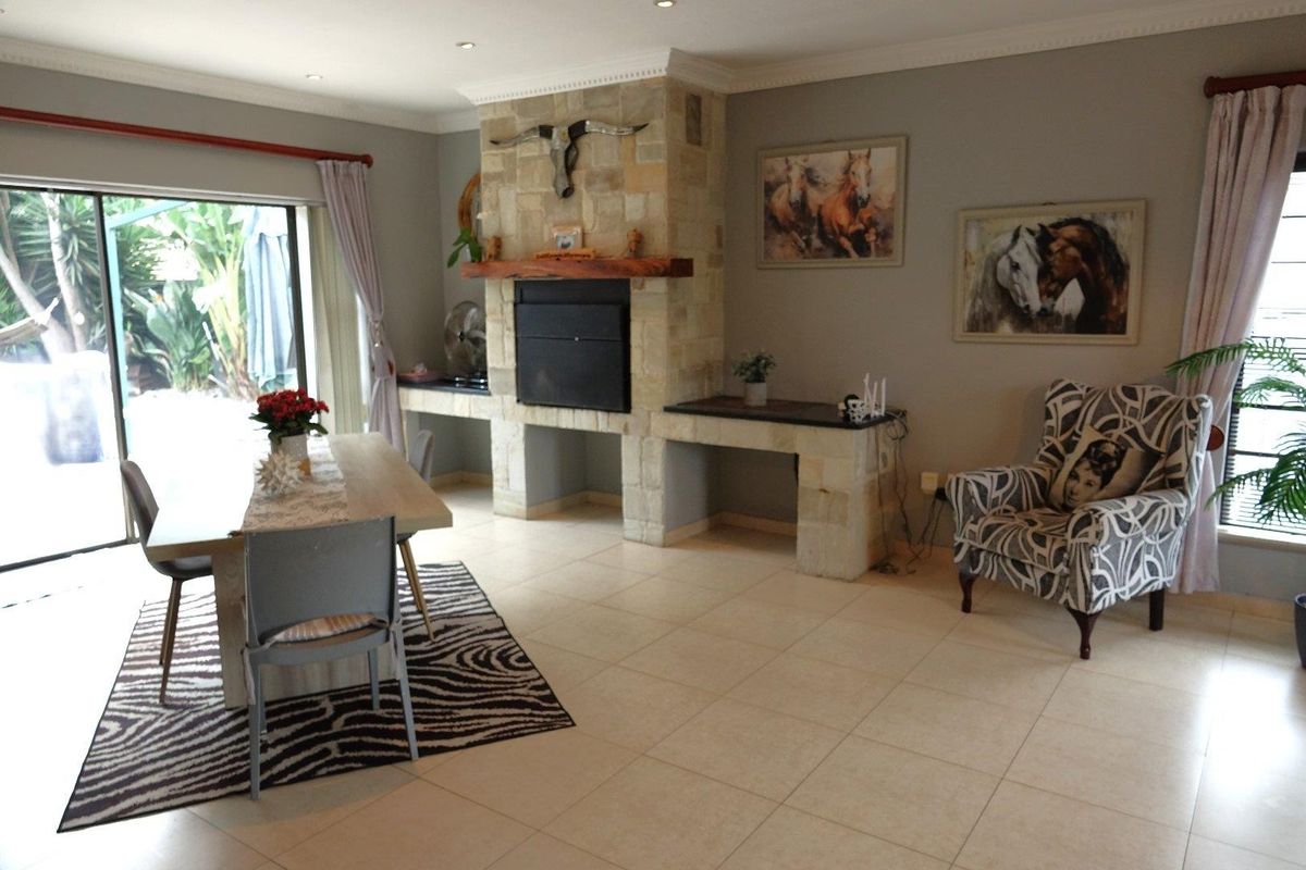 Spacious living area featuring a prominent stone fireplace with timber mantelpiece, ceramic tiled flooring, and large sliding doors providing access to the outdoor patio.