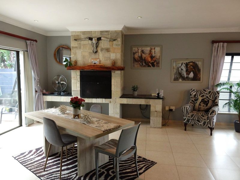 Spacious living area featuring a prominent stone fireplace with a timber mantelpiece, tiled flooring, and large sliding glass doors providing natural light.