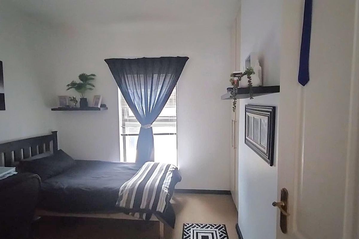 A functional bedroom featuring built-in cupboards and a window with natural light, providing a comfortable and practical living space.