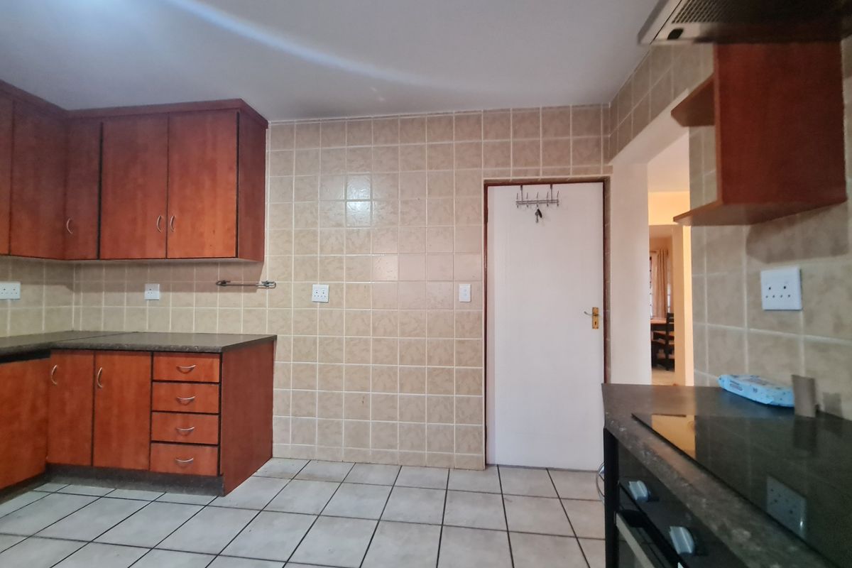 A functional kitchen featuring wooden cabinetry, tiled splashbacks, tiled flooring, and built-in cooking appliances, offering a clean and practical workspace.