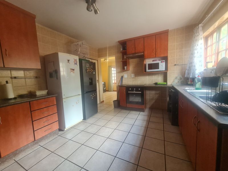 A functional kitchen featuring laminate cabinetry, built-in oven, extractor fan, and tiled flooring, offering a practical layout with ample storage space.