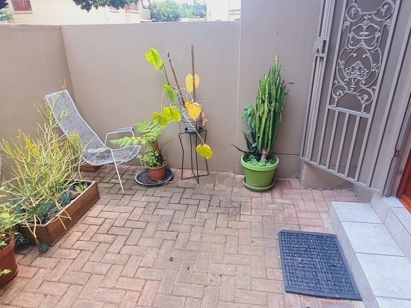 A private paved patio area featuring a secure metal gate and timber entrance door, providing a compact outdoor space.