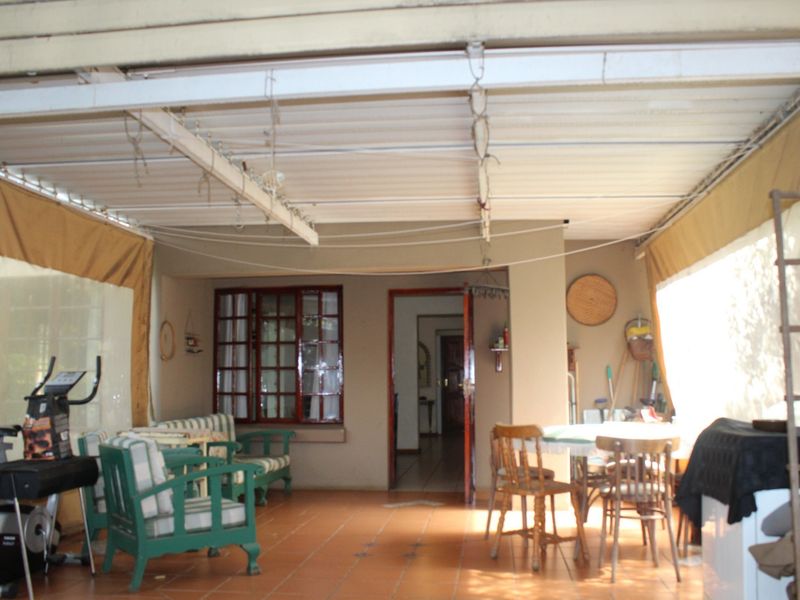 A covered patio area featuring tiled flooring and a corrugated metal roof, providing direct access to the interior of the townhouse.