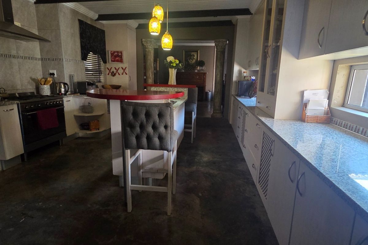 Spacious kitchen featuring granite countertops, built-in oven with extractor fan, and a central breakfast island, leading into an open-plan living area.