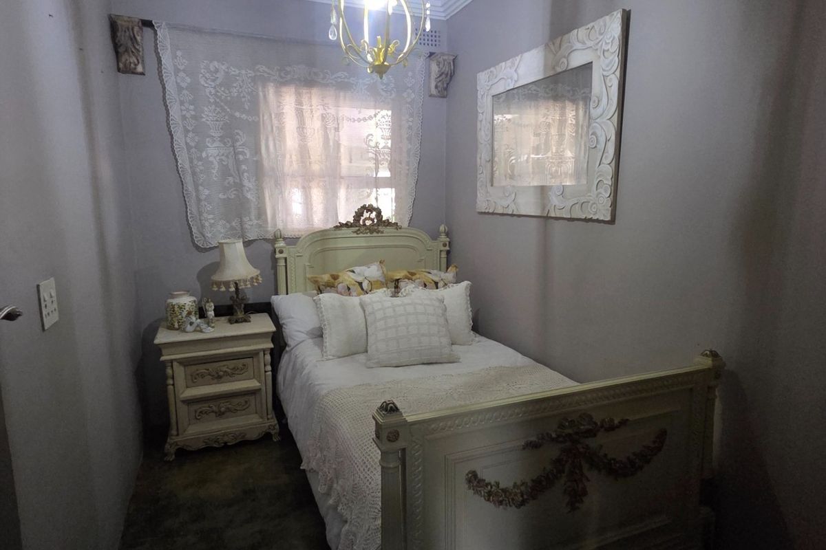 A compact bedroom featuring neutral wall tones, a classic window treatment, and a central ceiling light fixture.