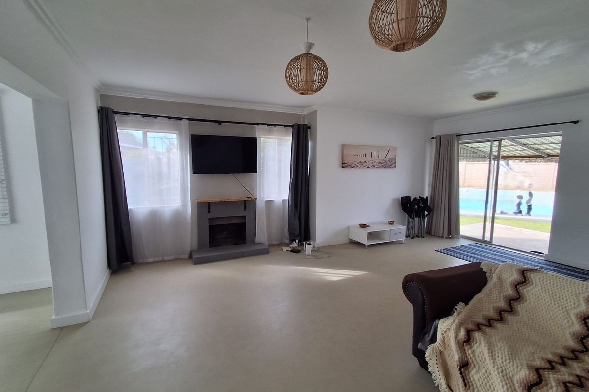Spacious living room featuring a fireplace, polished concrete floors, and large sliding glass doors providing direct access to the outdoor pool area.