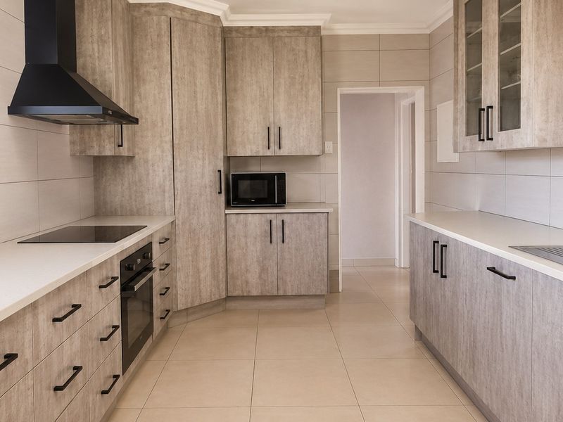 Modern kitchen featuring light wood-grain cabinetry, stone-look countertops, integrated appliances, and neutral tiled finishes throughout.