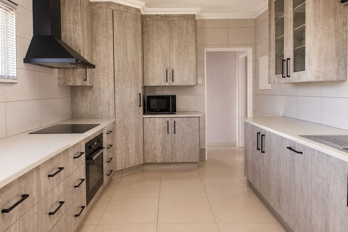 Modern kitchen featuring light wood-grain cabinetry, stone-look countertops, integrated appliances, and neutral tiled finishes throughout.