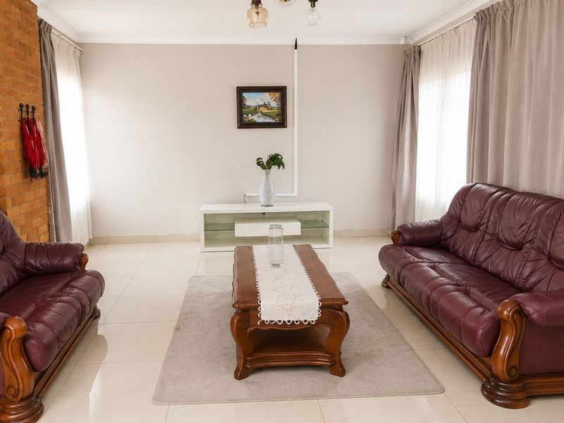 A spacious living room featuring tiled flooring and a prominent exposed brick feature wall, offering a neutral base for interior design updates.