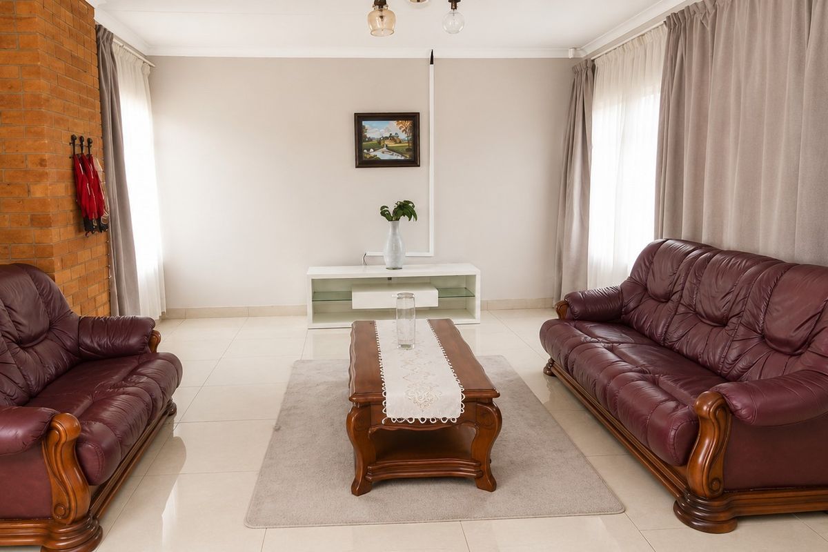 A spacious living room featuring tiled flooring and a prominent exposed brick feature wall, offering a neutral base for interior design updates.