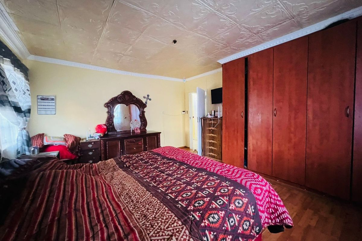 Spacious bedroom featuring built-in wooden wardrobes, decorative ceiling tiles, and laminate flooring, offering a functional layout with ample storage space.