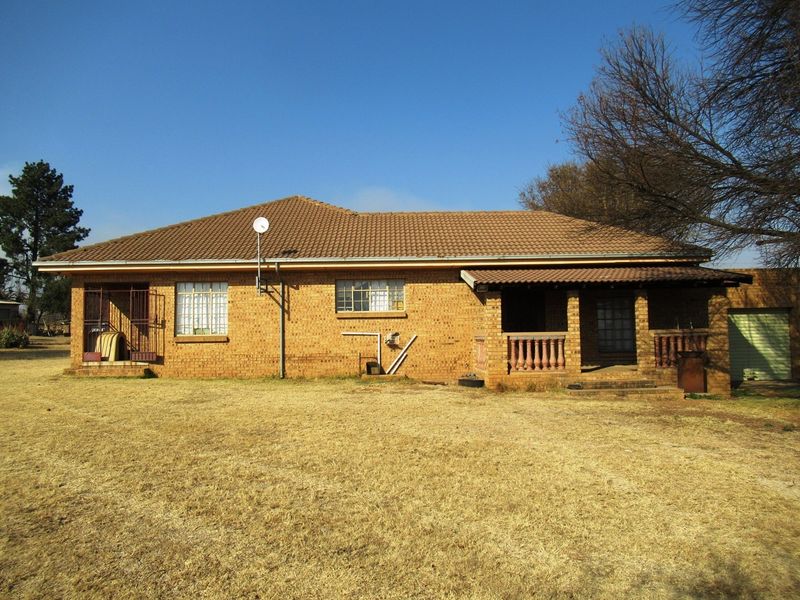 A view of the rear exterior of the face-brick small holding dwelling, featuring a covered patio area and established garden space.