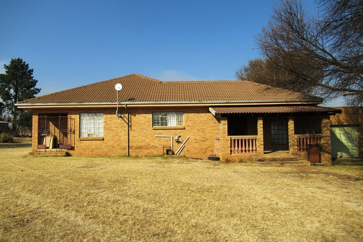 A view of the rear exterior of the face-brick small holding dwelling, featuring a covered patio area and established garden space.