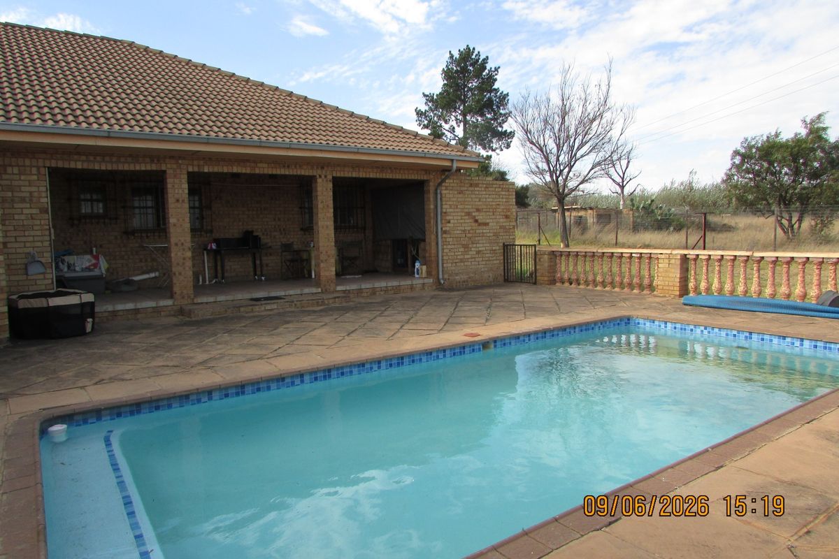Outdoor entertainment area featuring a covered patio, paved pool deck, and a swimming pool with a balustrade surround.
