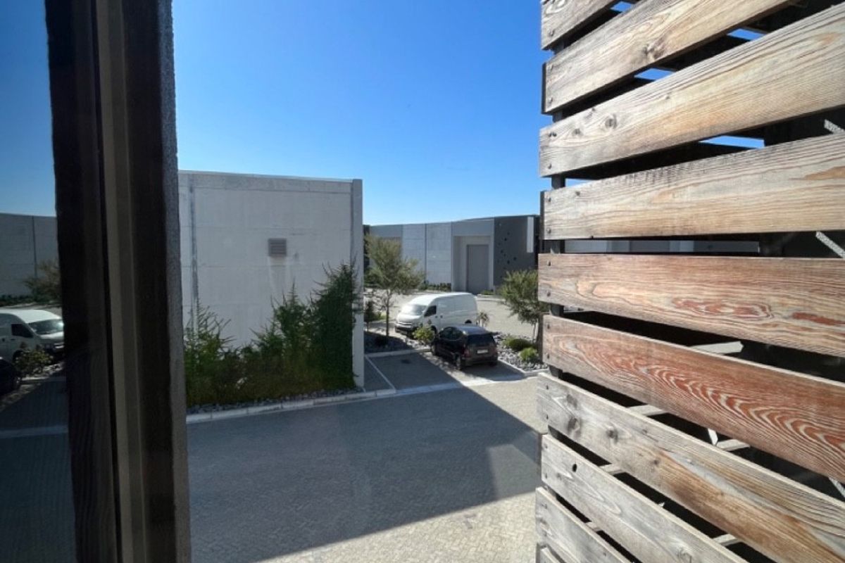View of the commercial property exterior, featuring a paved courtyard and timber slat privacy screening.